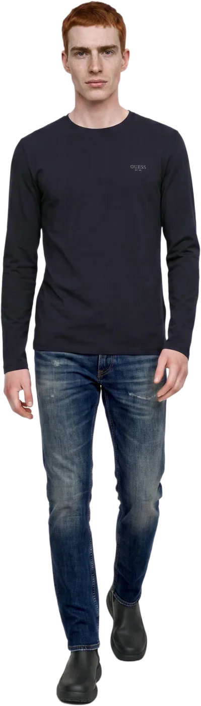 A model in a navy long-sleeve top and jeans, walking, full length